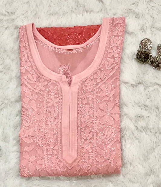 Pink embroidered top on a textured white surface