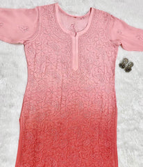Pink embroidered dress on a textured white background front photo