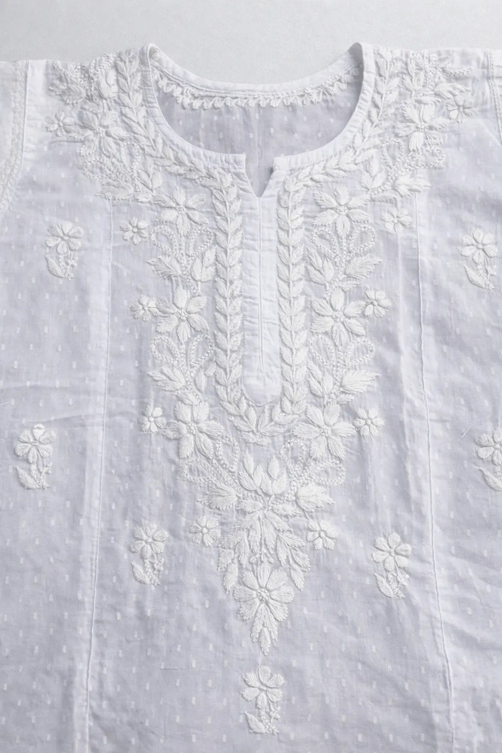 Flat lay of white Chikankari cotton kurti showcasing hand embroidered floral work